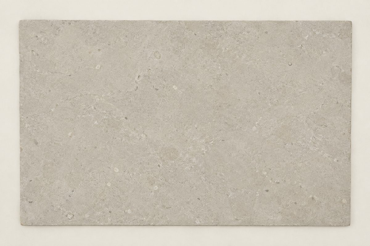 A slab of pale limestone photographed from directly above under flat frontal light. The surface reads as smooth and even.